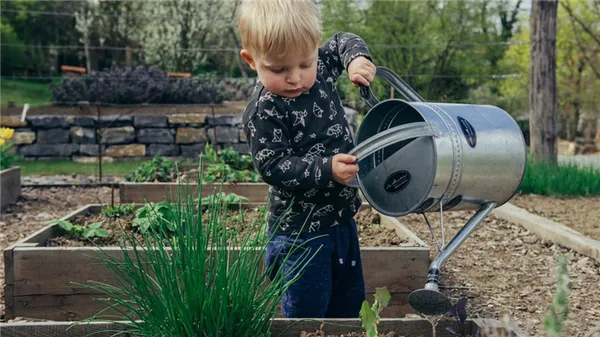 Мальчик поливает из лейки растения
